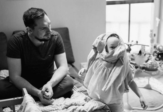Die kleine Tochter versucht ein Kleid anzuziehen