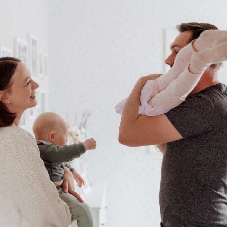 Frau hält ihr Baby während ihr Mann das Kind hält Frau hält ihr Baby während ihr Mann das Kind hält
